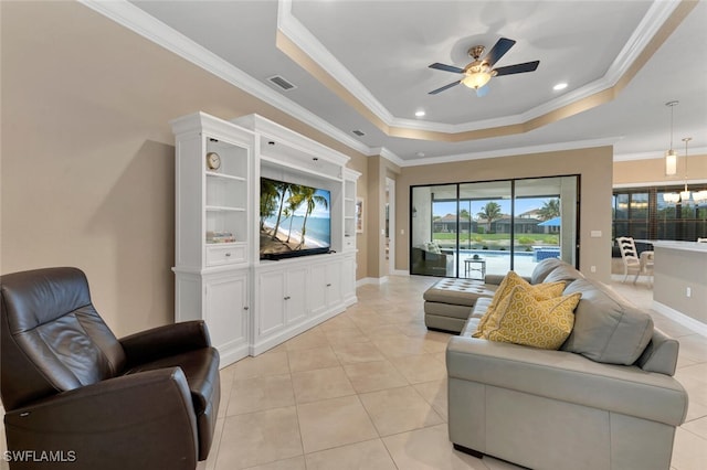 living area featuring light tile patterned flooring, visible vents, baseboards, a raised ceiling, and crown molding