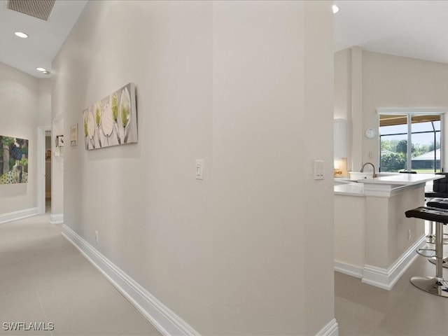 corridor with baseboards, visible vents, a sink, and recessed lighting