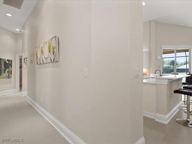 hall featuring recessed lighting, visible vents, baseboards, and a towering ceiling