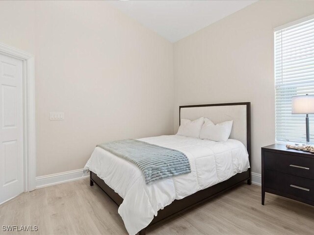 bedroom with multiple windows, baseboards, and wood finished floors