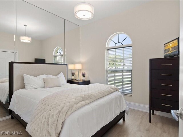 bedroom featuring light wood finished floors and baseboards