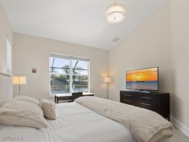 bedroom featuring light wood-style floors, visible vents, vaulted ceiling, and baseboards