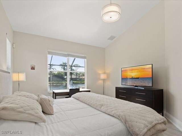 bedroom featuring lofted ceiling, wood finished floors, baseboards, and visible vents