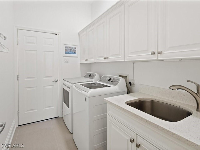 clothes washing area with washer and clothes dryer, light tile patterned floors, cabinet space, and a sink