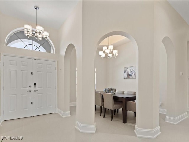 entrance foyer with baseboards, arched walkways, tile patterned floors, and an inviting chandelier