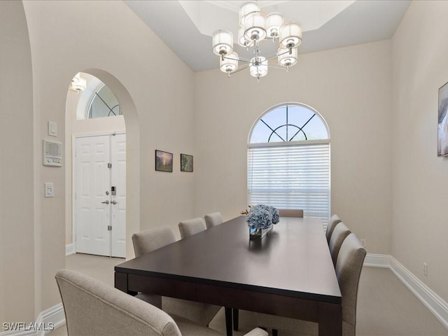 dining area featuring arched walkways, baseboards, and an inviting chandelier