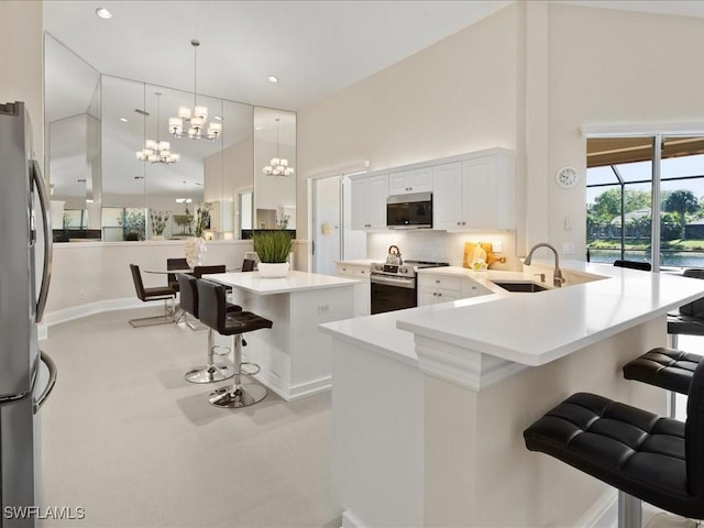 kitchen with a sink, a kitchen breakfast bar, stainless steel appliances, a peninsula, and a towering ceiling