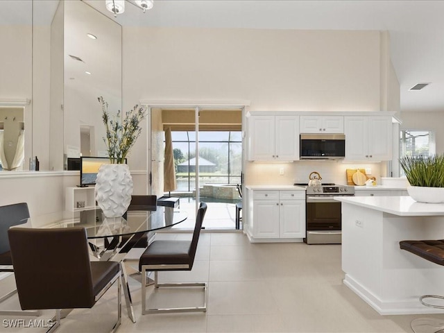 kitchen featuring light countertops, appliances with stainless steel finishes, a high ceiling, and white cabinets