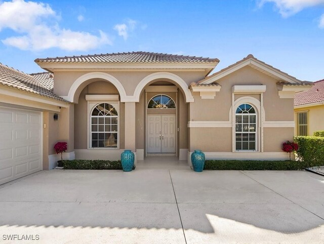 doorway to property with an attached garage, driveway, and stucco siding