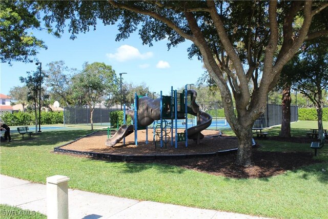 community jungle gym featuring a lawn and fence