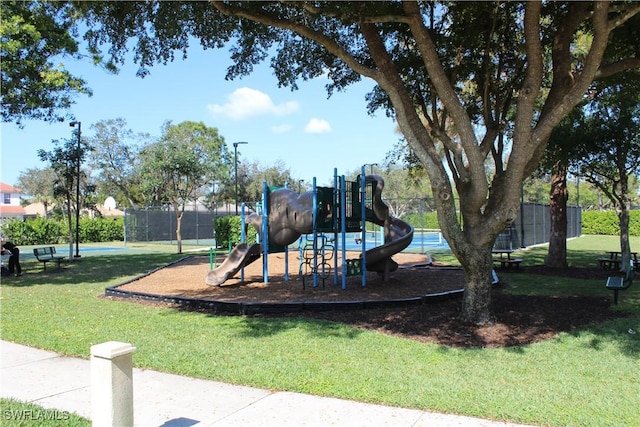 community jungle gym with a lawn and fence