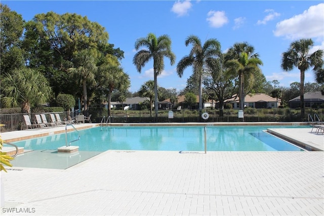 community pool with a patio area and fence