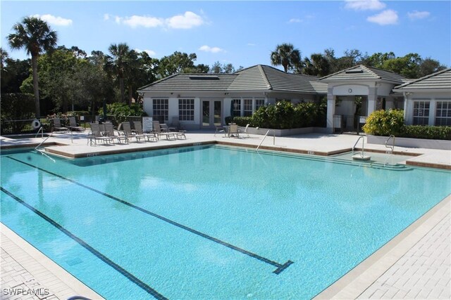 pool with french doors, a patio area, and fence