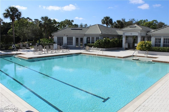 community pool with french doors, fence, and a patio area