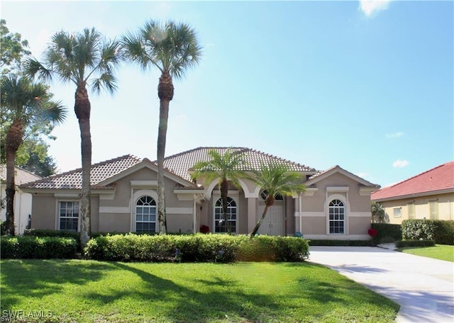 mediterranean / spanish house with a front yard, driveway, and stucco siding