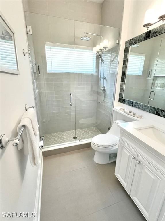 bathroom featuring toilet, a stall shower, vanity, and tile patterned flooring