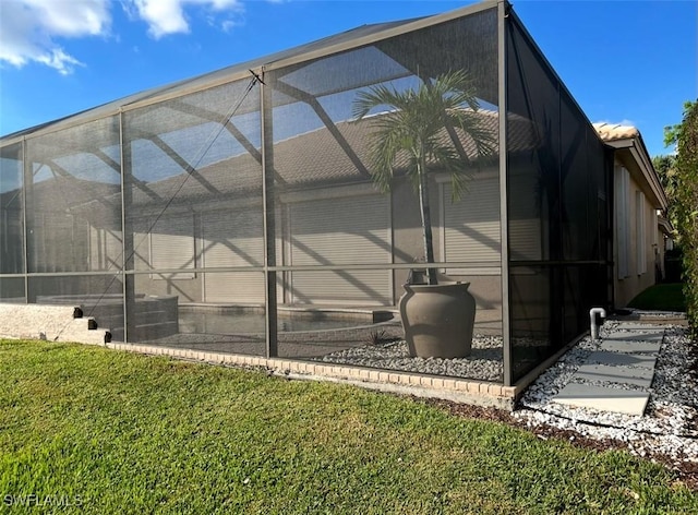 view of side of property featuring a lawn and a lanai