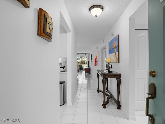 corridor with light tile patterned flooring and a textured ceiling