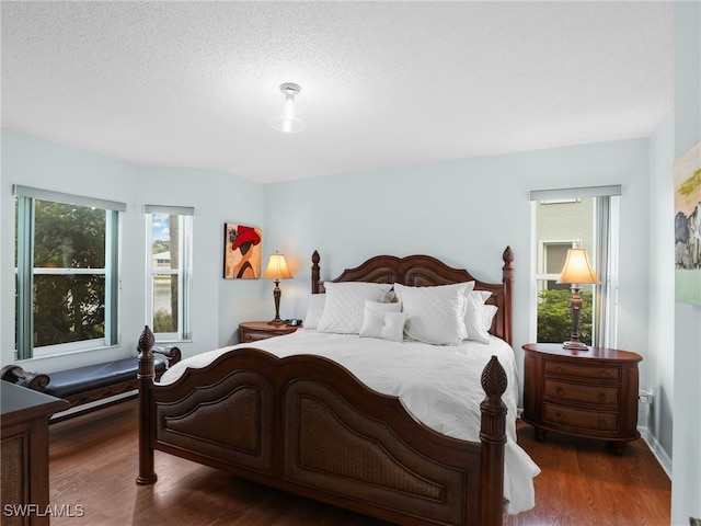 bedroom with a textured ceiling and dark hardwood / wood-style floors