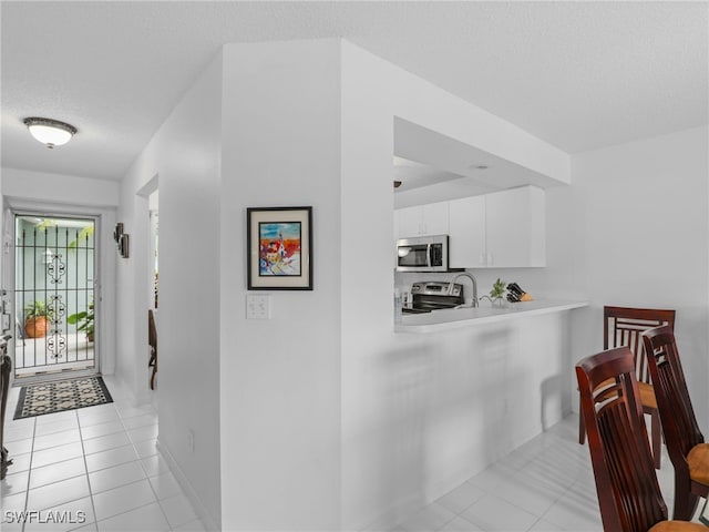 hall with a textured ceiling and light tile patterned flooring