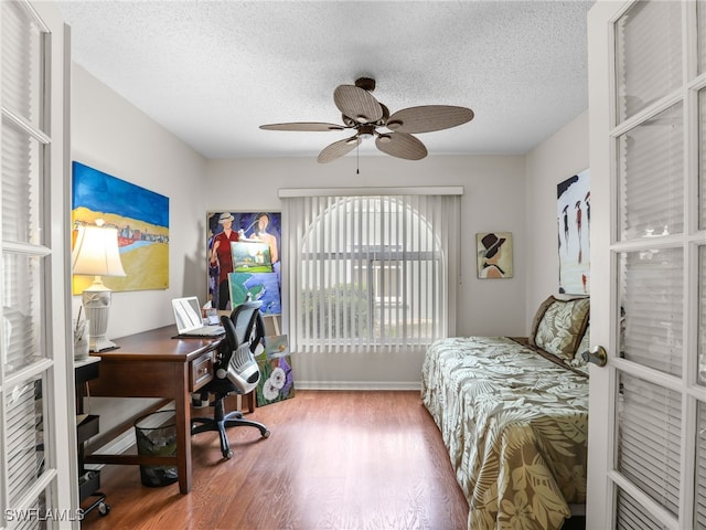 bedroom with ceiling fan, hardwood / wood-style floors, and a textured ceiling