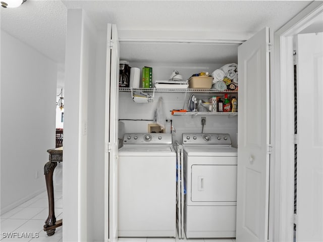 laundry area featuring light tile patterned flooring, a textured ceiling, and washing machine and clothes dryer