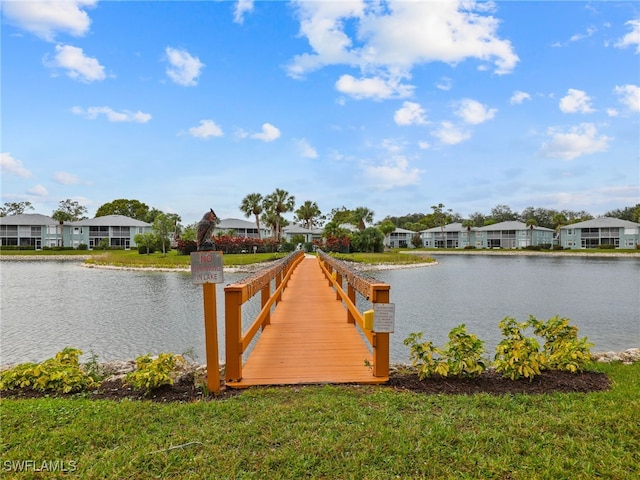 view of dock with a lawn and a water view