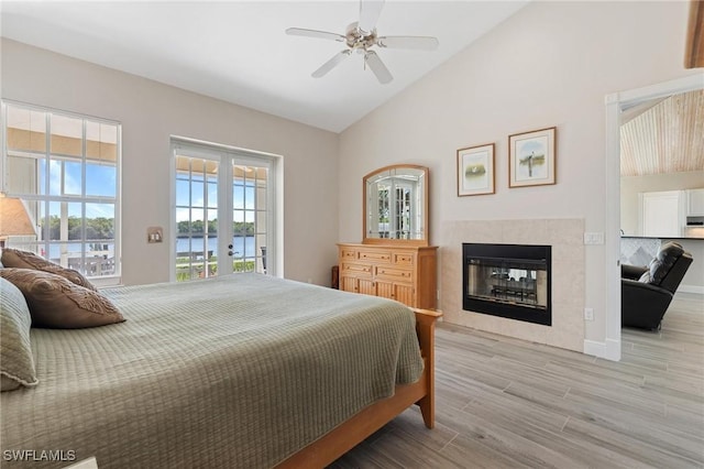 bedroom with access to outside, french doors, a water view, ceiling fan, and light hardwood / wood-style floors