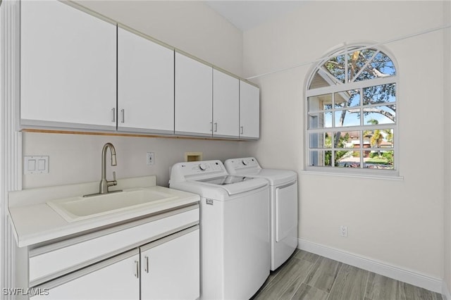 washroom featuring washer and clothes dryer, cabinets, light wood-type flooring, and sink