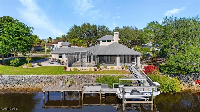 rear view of property featuring glass enclosure, a water view, and a yard