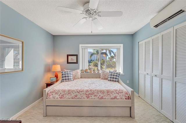 bedroom with ceiling fan, a wall mounted AC, a closet, and a textured ceiling