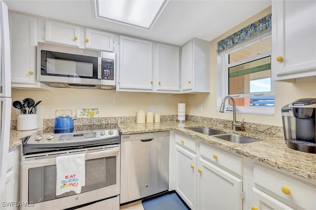 kitchen with appliances with stainless steel finishes, white cabinets, light stone counters, and sink