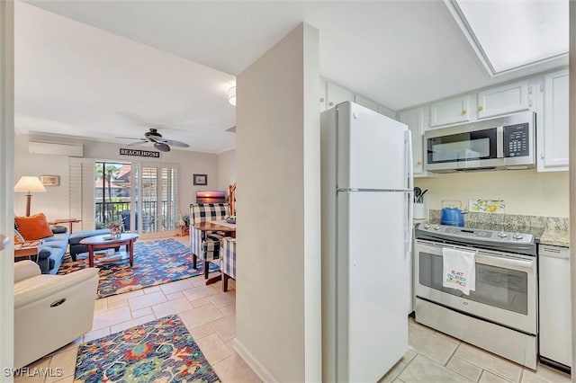 kitchen featuring an AC wall unit, light tile patterned floors, white cabinets, appliances with stainless steel finishes, and ceiling fan