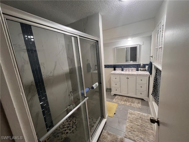 bathroom with vanity, an enclosed shower, and a textured ceiling