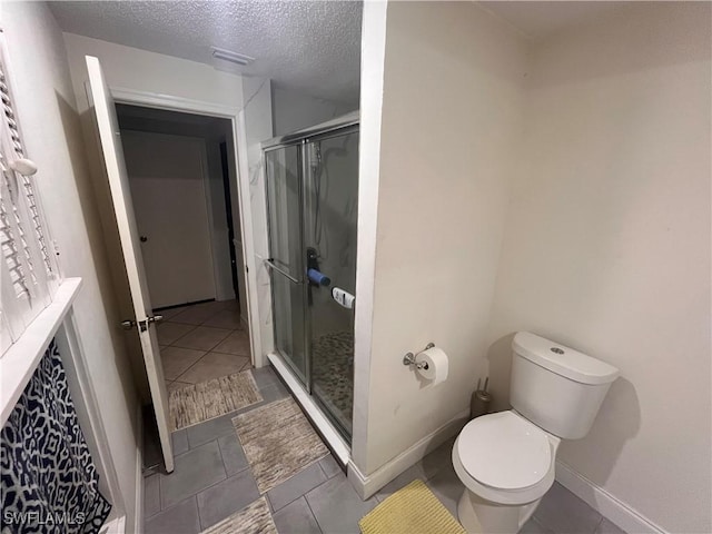 bathroom featuring toilet, tile patterned flooring, a shower with door, and a textured ceiling