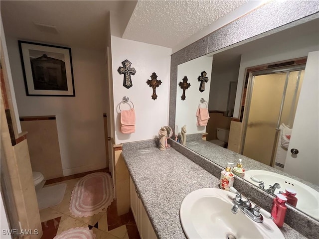 bathroom with tile patterned flooring, vanity, a textured ceiling, and toilet