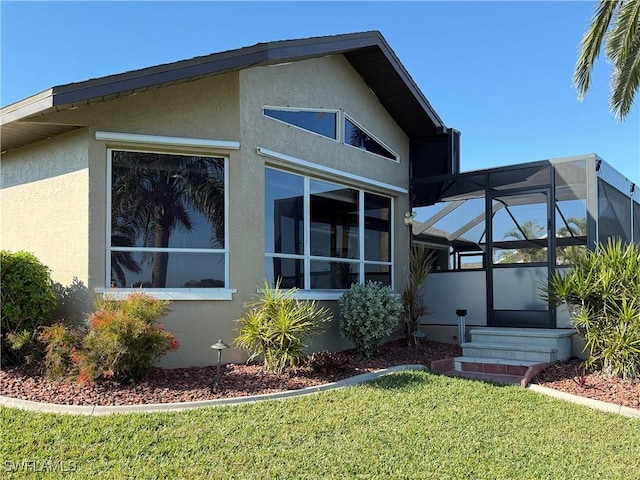 view of property exterior featuring glass enclosure and a yard