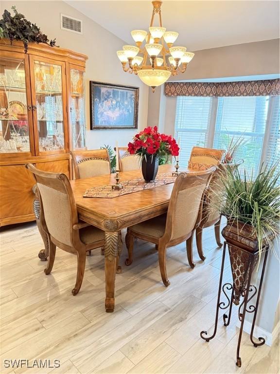 dining room with light hardwood / wood-style floors, lofted ceiling, and a chandelier