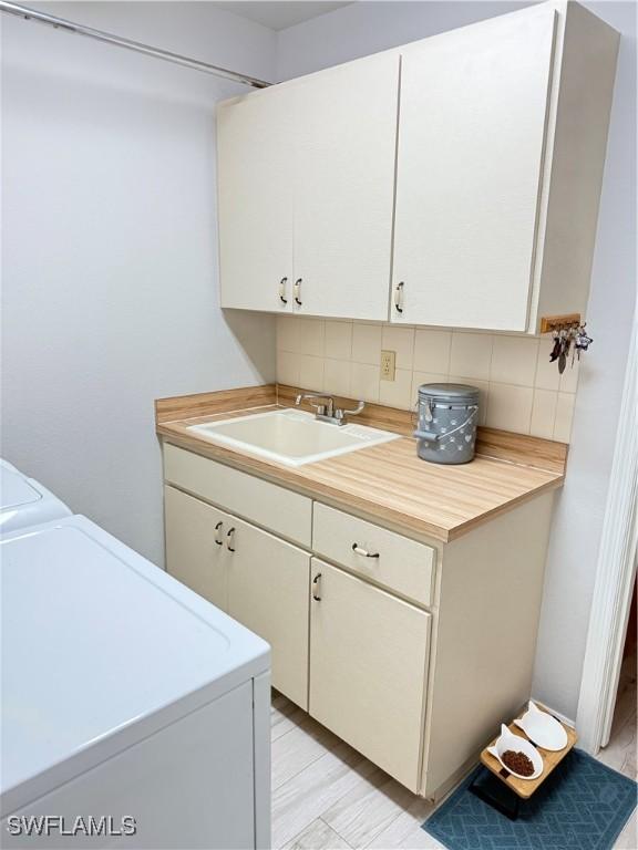 laundry area with washer and clothes dryer, sink, and cabinets