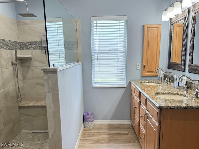 bathroom featuring hardwood / wood-style flooring, vanity, and tiled shower