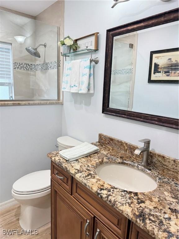 bathroom featuring vanity, toilet, and a tile shower