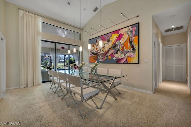 dining room with high vaulted ceiling and light colored carpet