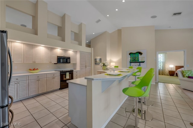 kitchen with black appliances, a breakfast bar, high vaulted ceiling, and light tile patterned floors