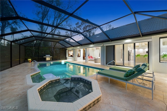 pool at dusk featuring a patio area, grilling area, an in ground hot tub, and glass enclosure