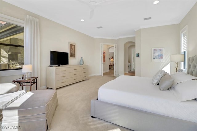 bedroom with arched walkways, recessed lighting, visible vents, and light colored carpet