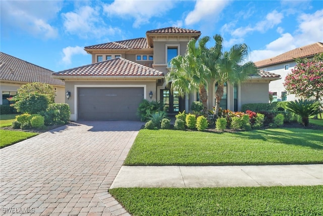 mediterranean / spanish-style home with decorative driveway, stucco siding, a garage, a tiled roof, and a front lawn