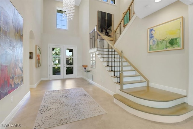 entrance foyer with stairs, french doors, a towering ceiling, and baseboards