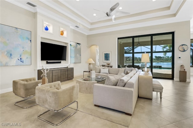 living room with visible vents, arched walkways, a tray ceiling, and ornamental molding