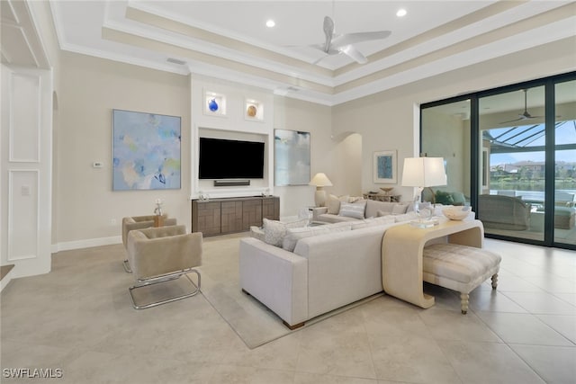 living area featuring arched walkways, ceiling fan, ornamental molding, and a raised ceiling