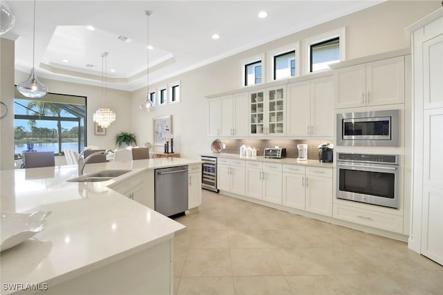 kitchen featuring glass insert cabinets, stainless steel appliances, white cabinetry, pendant lighting, and a sink